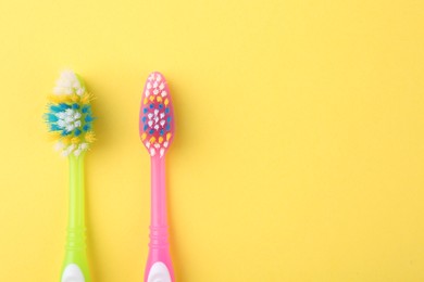 Photo of Colorful plastic toothbrushes on yellow background, flat lay. Space for text