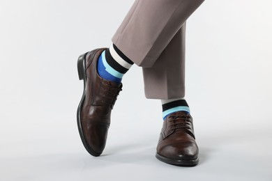Photo of Man in stylish colorful socks, shoes and pants on white background, closeup