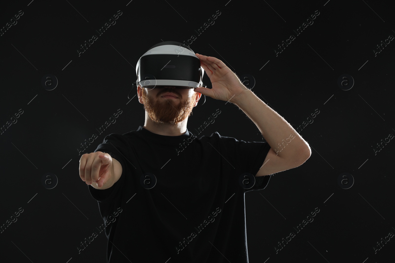 Photo of Man using virtual reality headset on black background