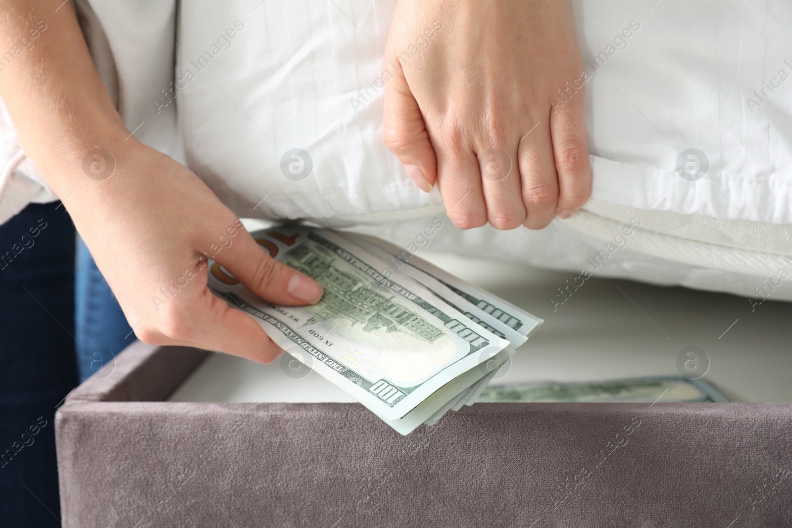 Photo of Woman hiding dollar banknotes under mattress in bedroom, closeup. Money savings