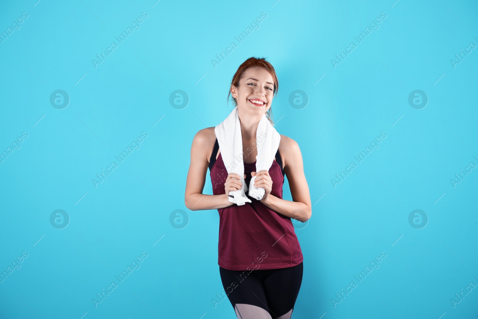 Photo of Beautiful young woman in sportswear with towel on color background