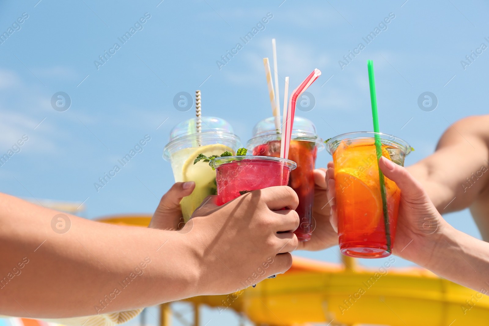 Photo of People with refreshing drinks in water park, closeup