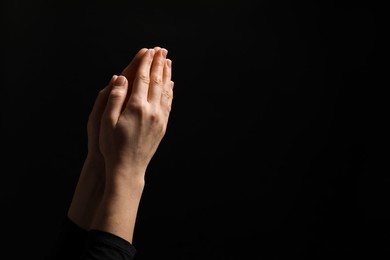 Photo of Religion. Christian woman praying on black background, closeup. Space for text