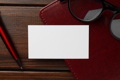 Photo of Blank business card, notebook, glasses and pen on wooden table, flat lay. Mockup for design