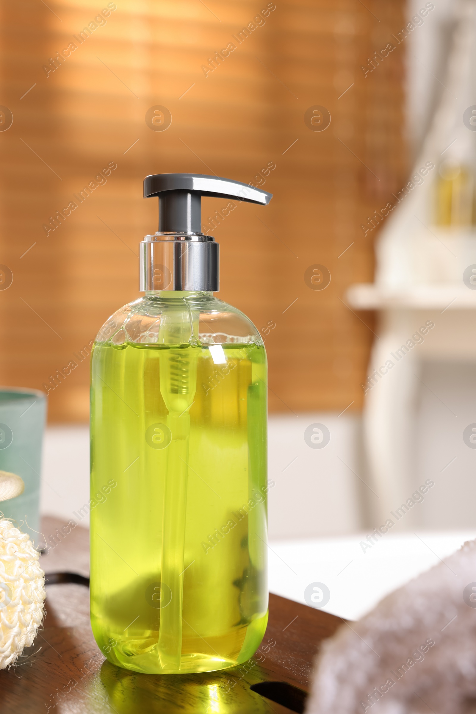 Photo of Dispenser of liquid soap on wooden board in bathroom