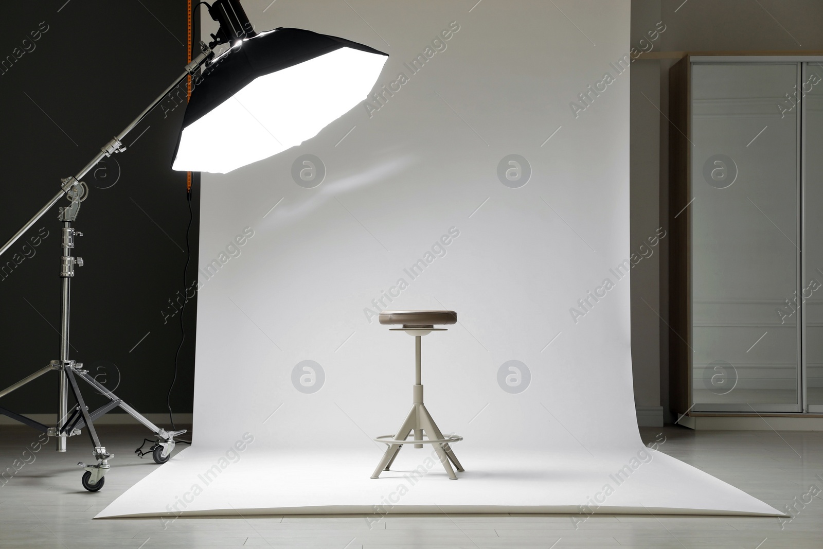 Photo of White photo background, stool and professional lighting equipment in modern studio