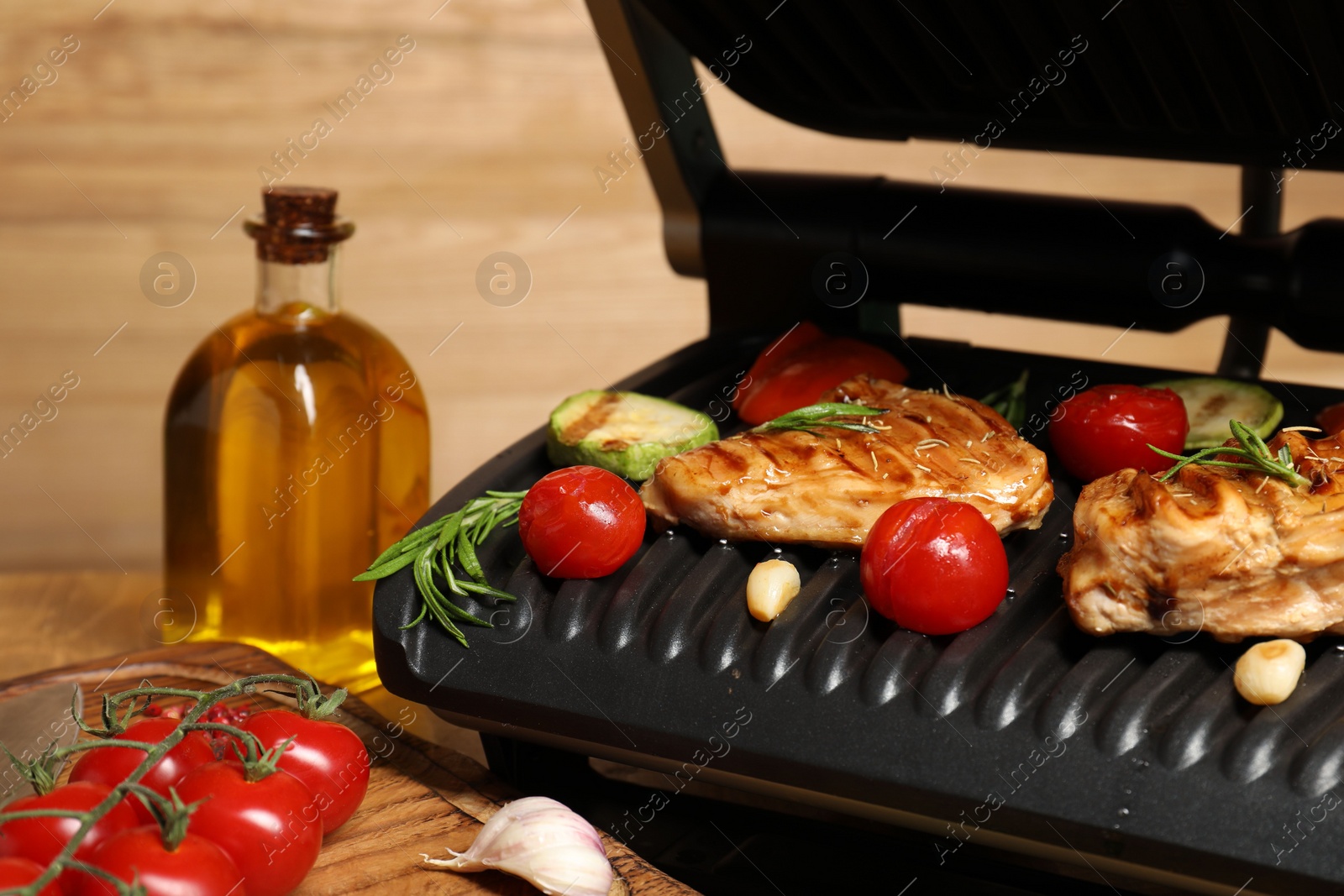 Photo of Electric grill with different products on table