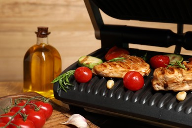 Photo of Electric grill with different products on table