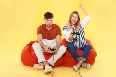 Photo of Emotional couple playing video games with controllers on color background