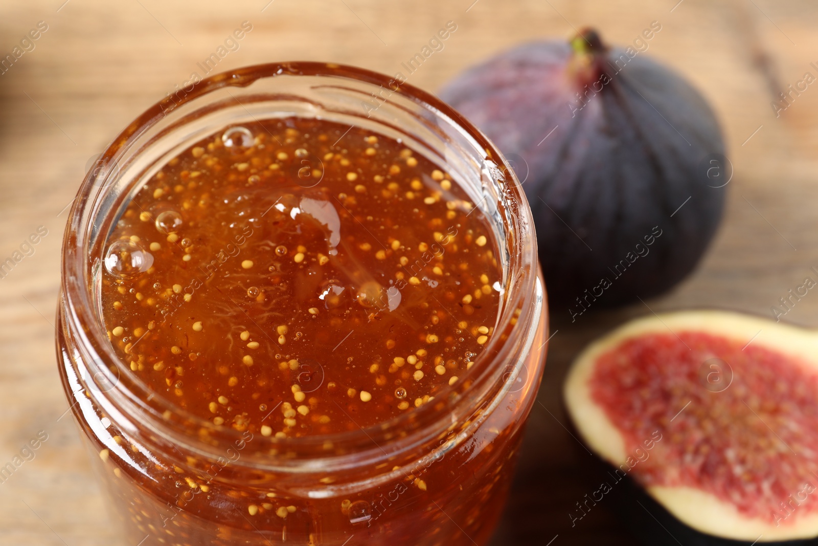 Photo of Glass jar with tasty sweet jam and fresh figs on table, closeup