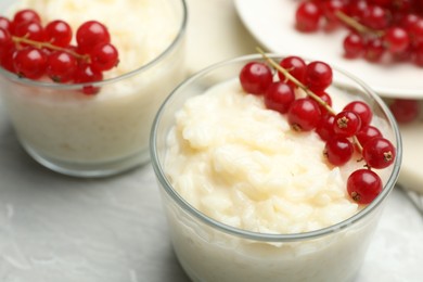 Photo of Delicious rice pudding with redcurrant on marble table, closeup