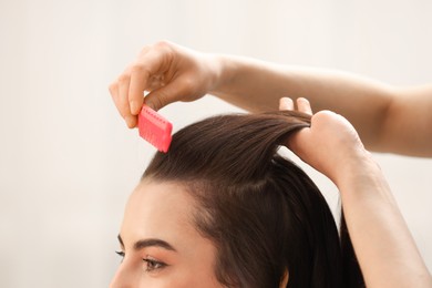 Photo of Hair styling. Professional hairdresser combing woman's hair indoors, closeup