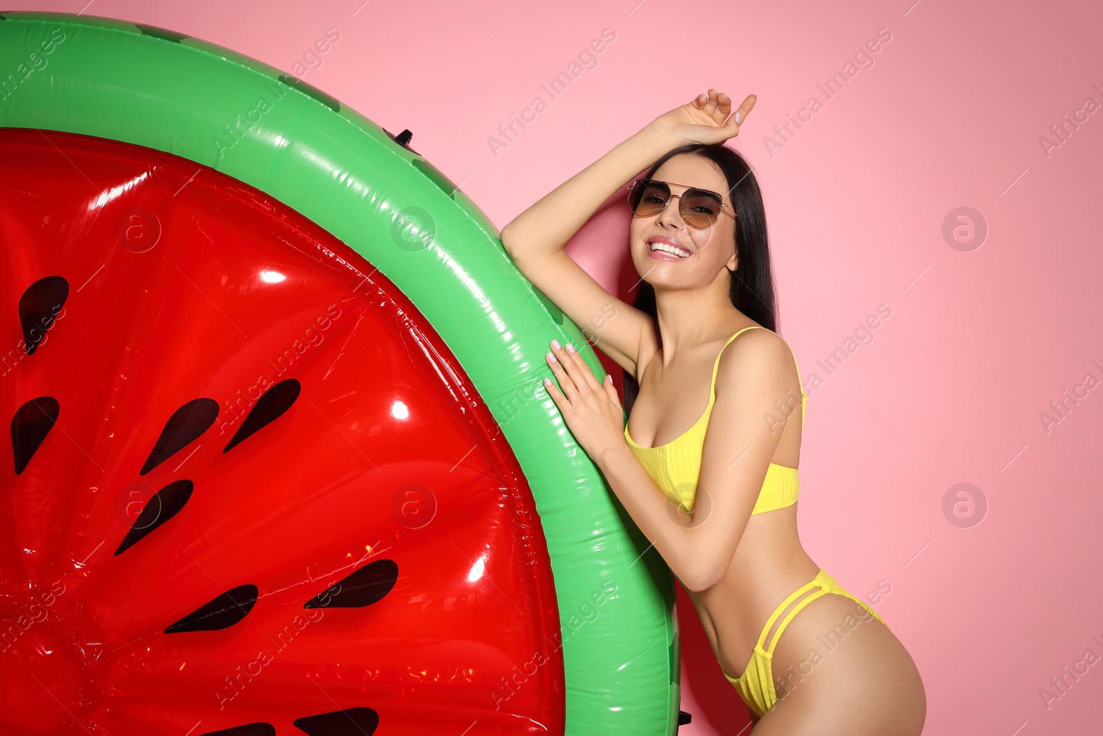 Photo of Young woman with stylish sunglasses near inflatable mattress against pink background