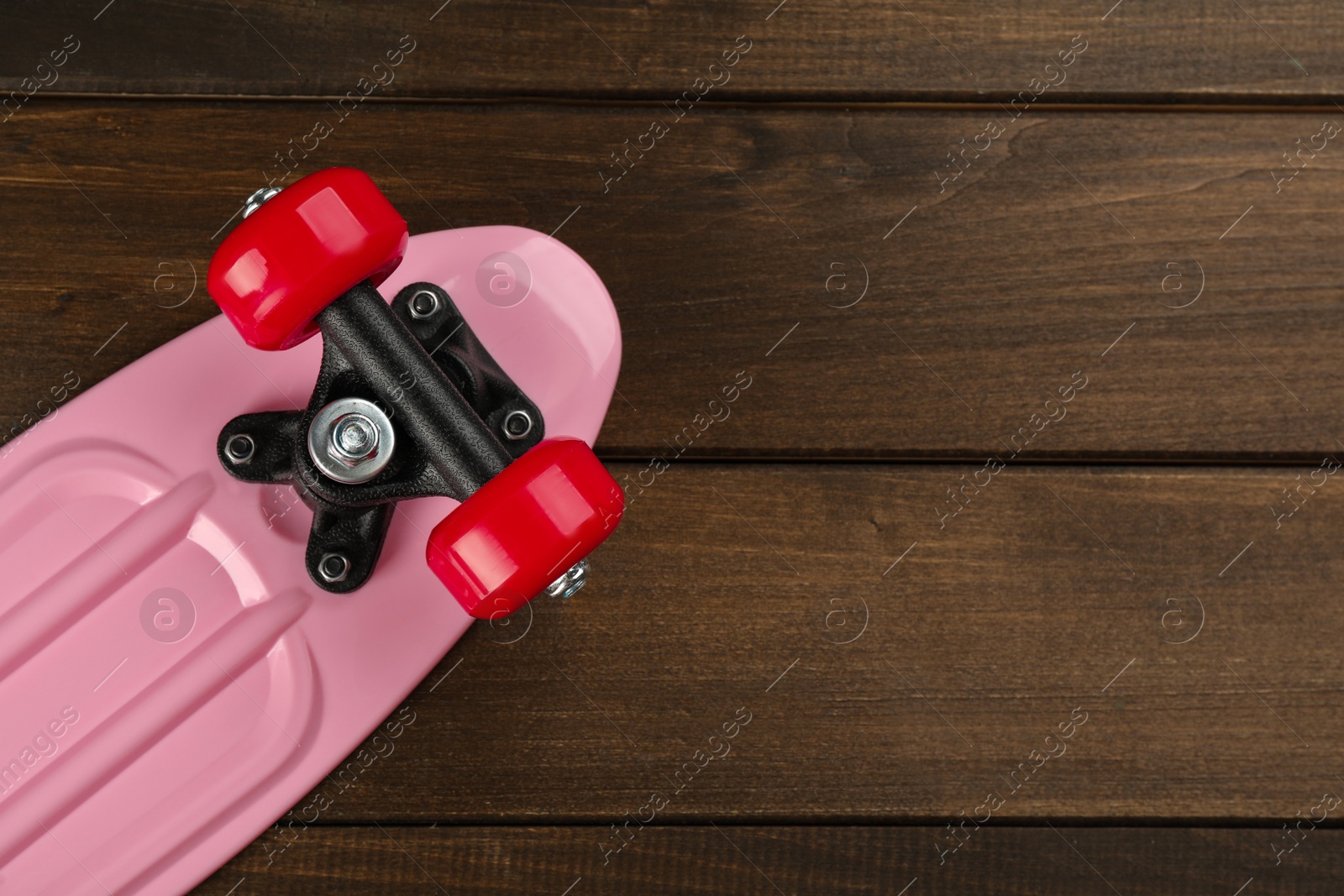 Photo of Pink skateboard on wooden background, top view. Space for text