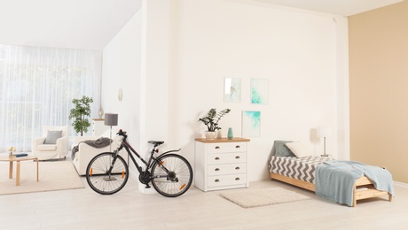 Photo of Bicycle near light wall in stylish room interior