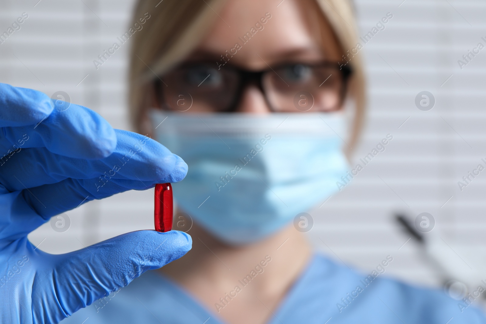 Photo of Doctor holding pill on light background, selective focus. Space for text