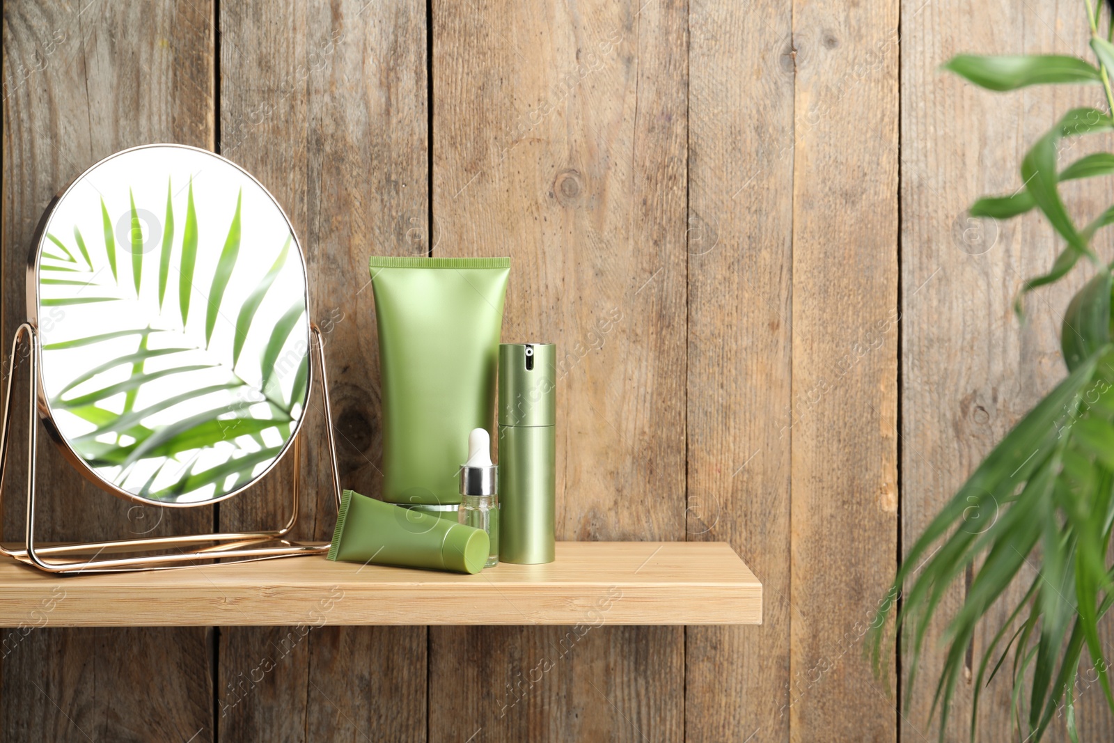 Photo of Set of cosmetic products and mirror on shelf near wooden wall