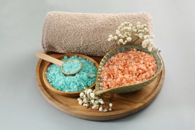 Aromatic sea salt, beautiful flowers and towel on light grey background