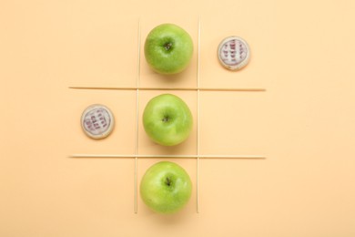 Tic tac toe game made with apples and cookies on beige background, top view