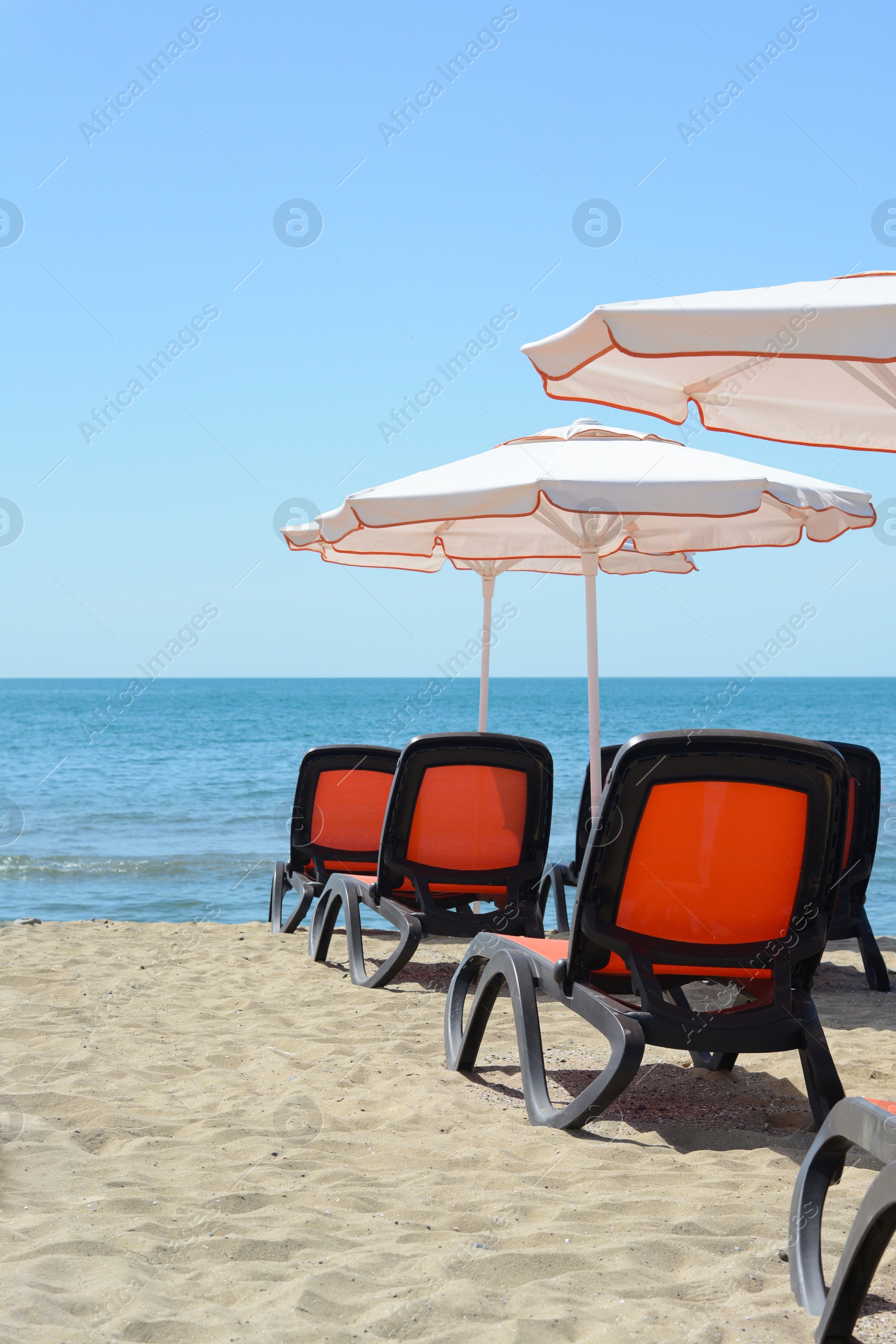 Photo of Empty sunbeds and beach umbrellas at tropical resort on sunny day