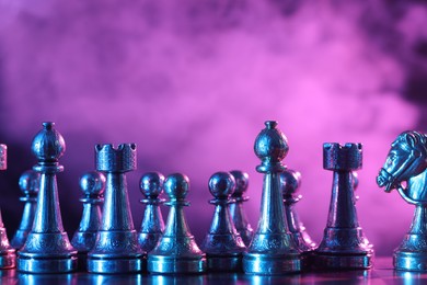 Photo of Chess pieces on checkerboard in color light. Space for text