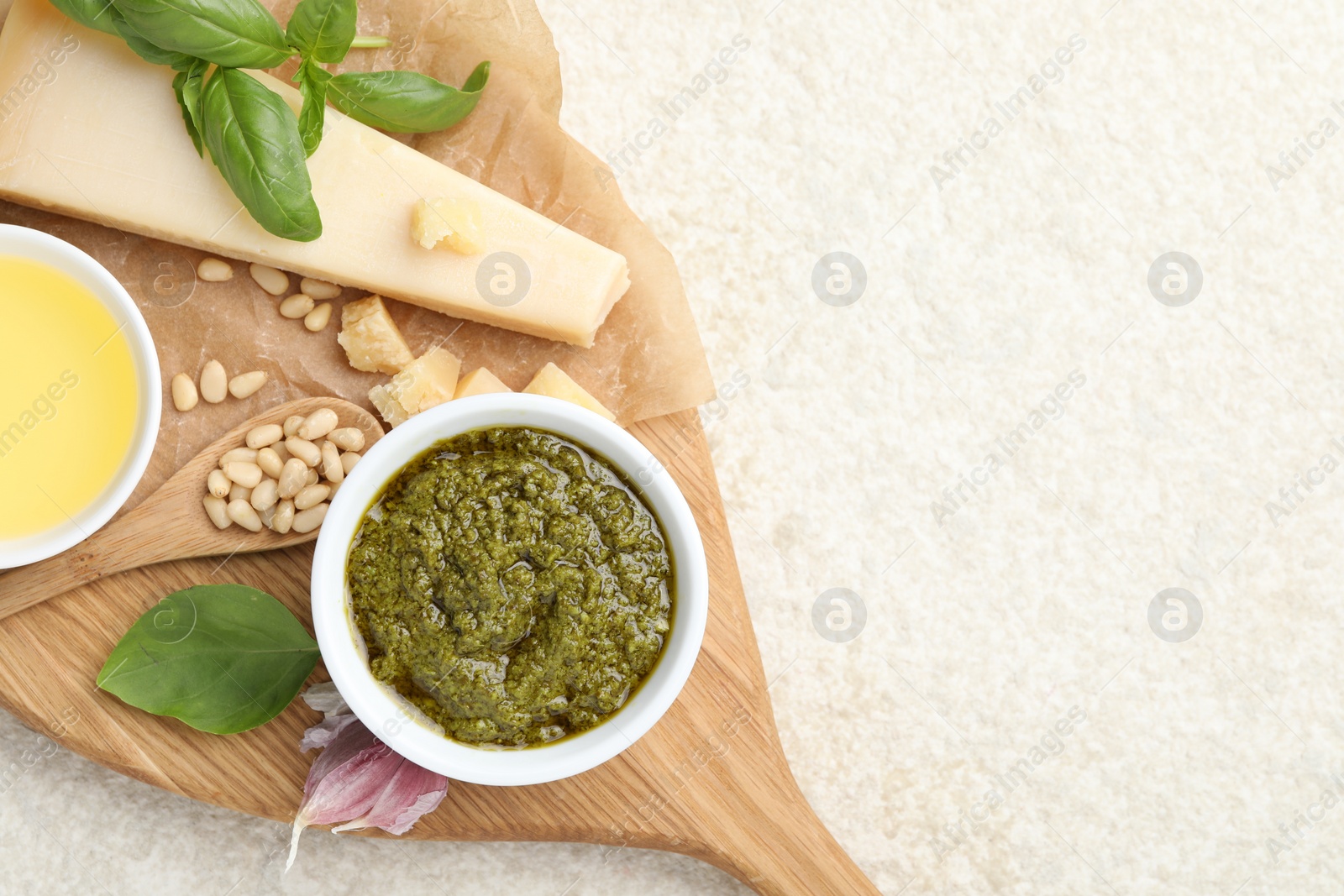 Photo of Tasty pesto sauce, basil, pine nuts, garlic, oil and cheese on light grey table, top view. Space for text