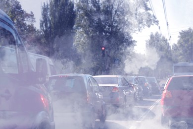 Image of Environmental pollution. Air contaminated with fumes in city. Cars surrounded by exhaust on road