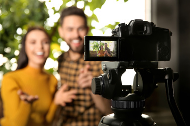 Photo of Young bloggers recording video indoors, focus on camera screen