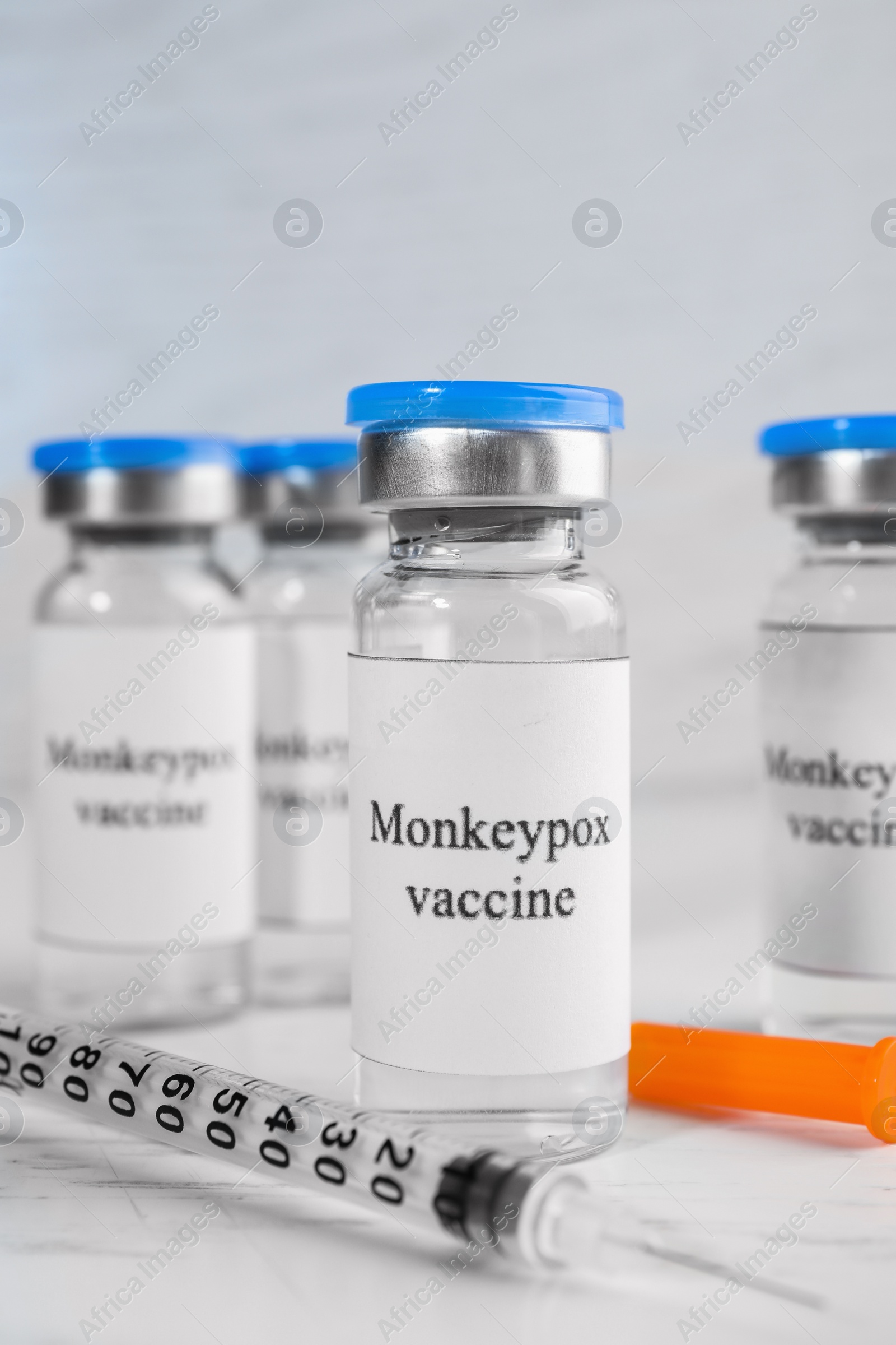 Photo of Monkeypox vaccine in glass vials and syringe on white wooden table