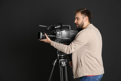 Operator with professional video camera on black background