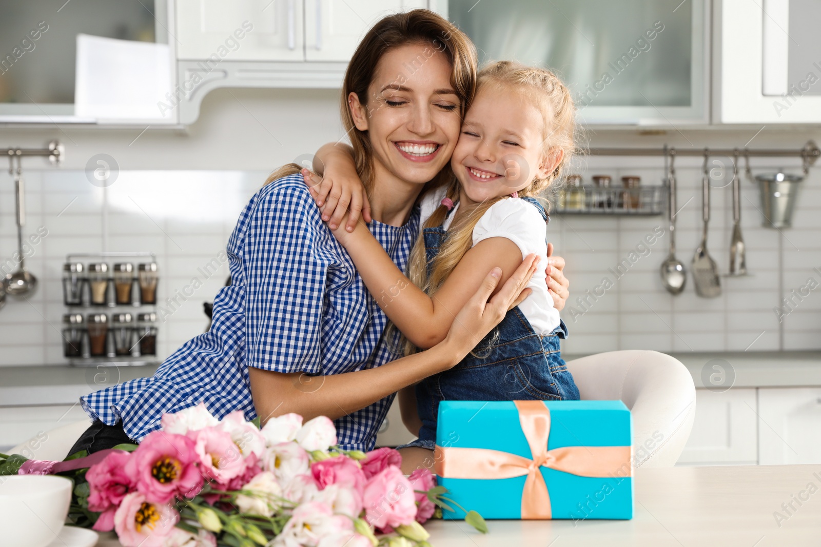 Photo of Little daughter congratulating her mom in kitchen. Happy Mother's Day