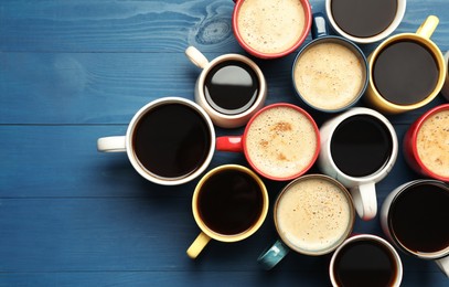 Photo of Many cups of different coffee drinks on blue wooden table, flat lay. Space for text