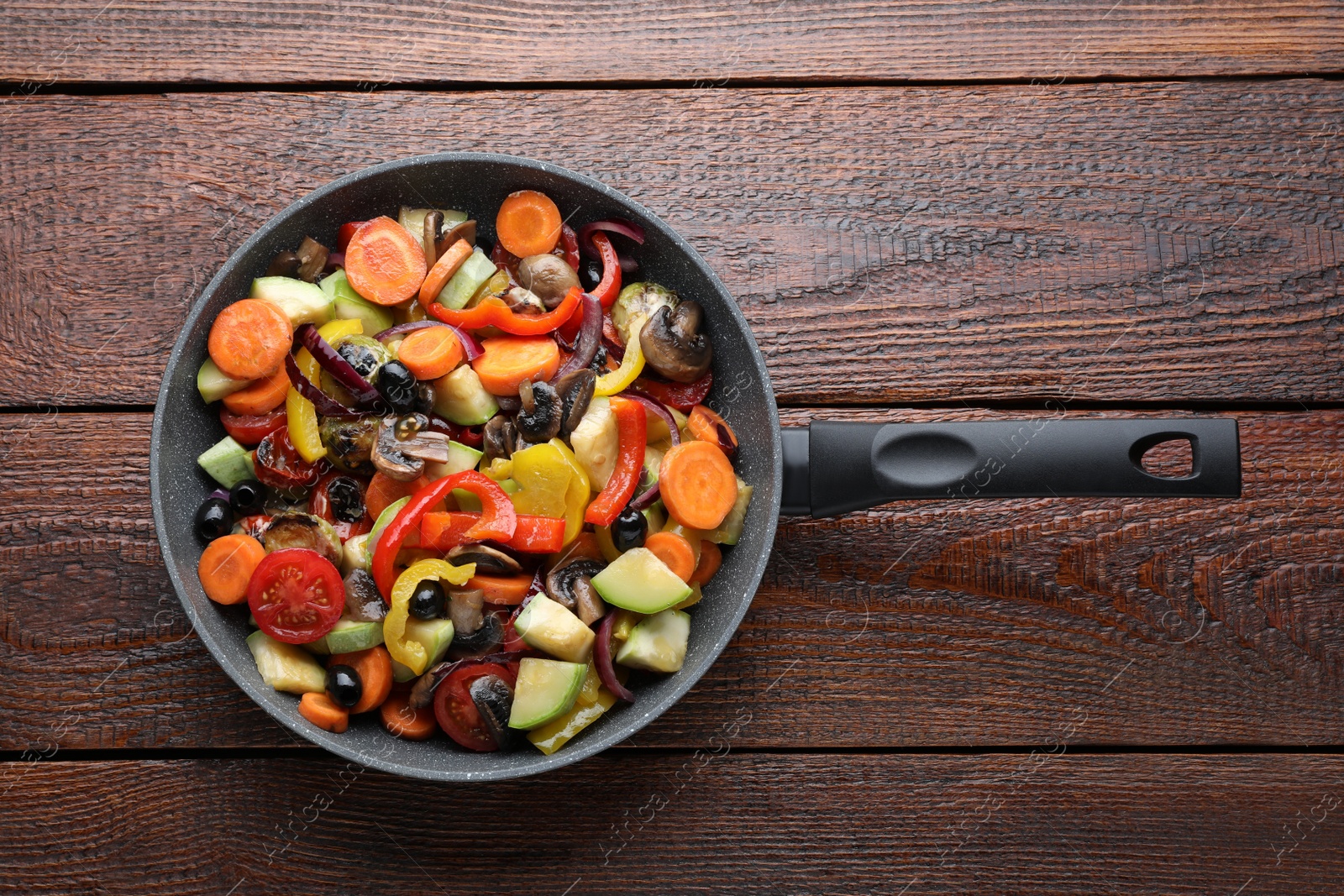Photo of Mix of tasty vegetables in pan on wooden table, top view