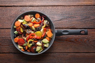Photo of Mix of tasty vegetables in pan on wooden table, top view