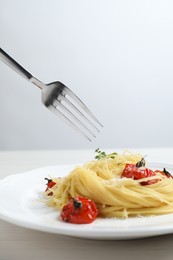 Photo of Eating tasty capellini with tomatoes and cheese at white wooden table, closeup. Exquisite presentation of pasta dish