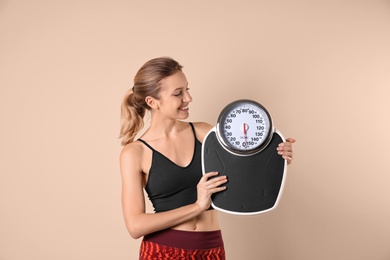 Photo of Young beautiful woman with scales on light background. Weight loss motivation