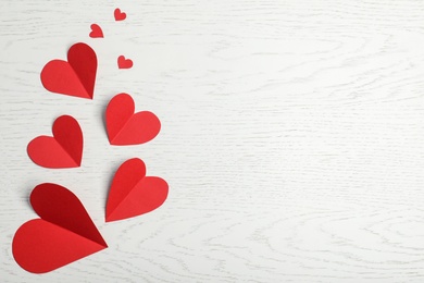 Photo of Flat lay composition with paper hearts and space for text on white wooden background