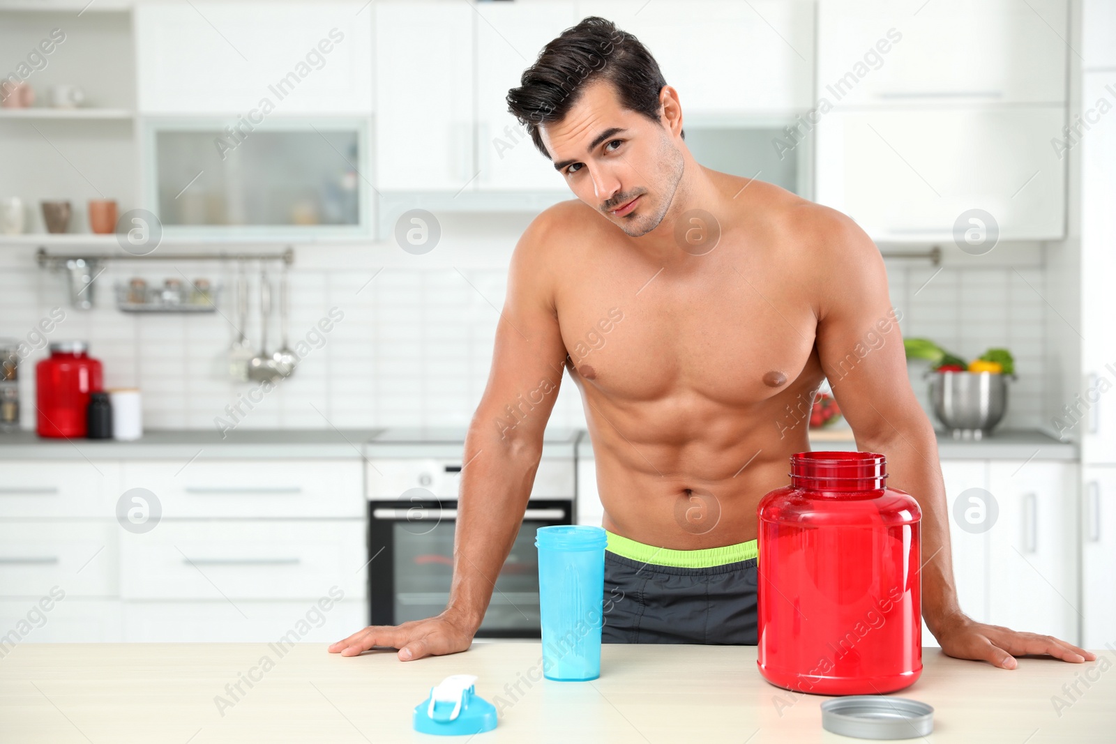 Photo of Young shirtless athletic man with protein shake powder in kitchen, space for text