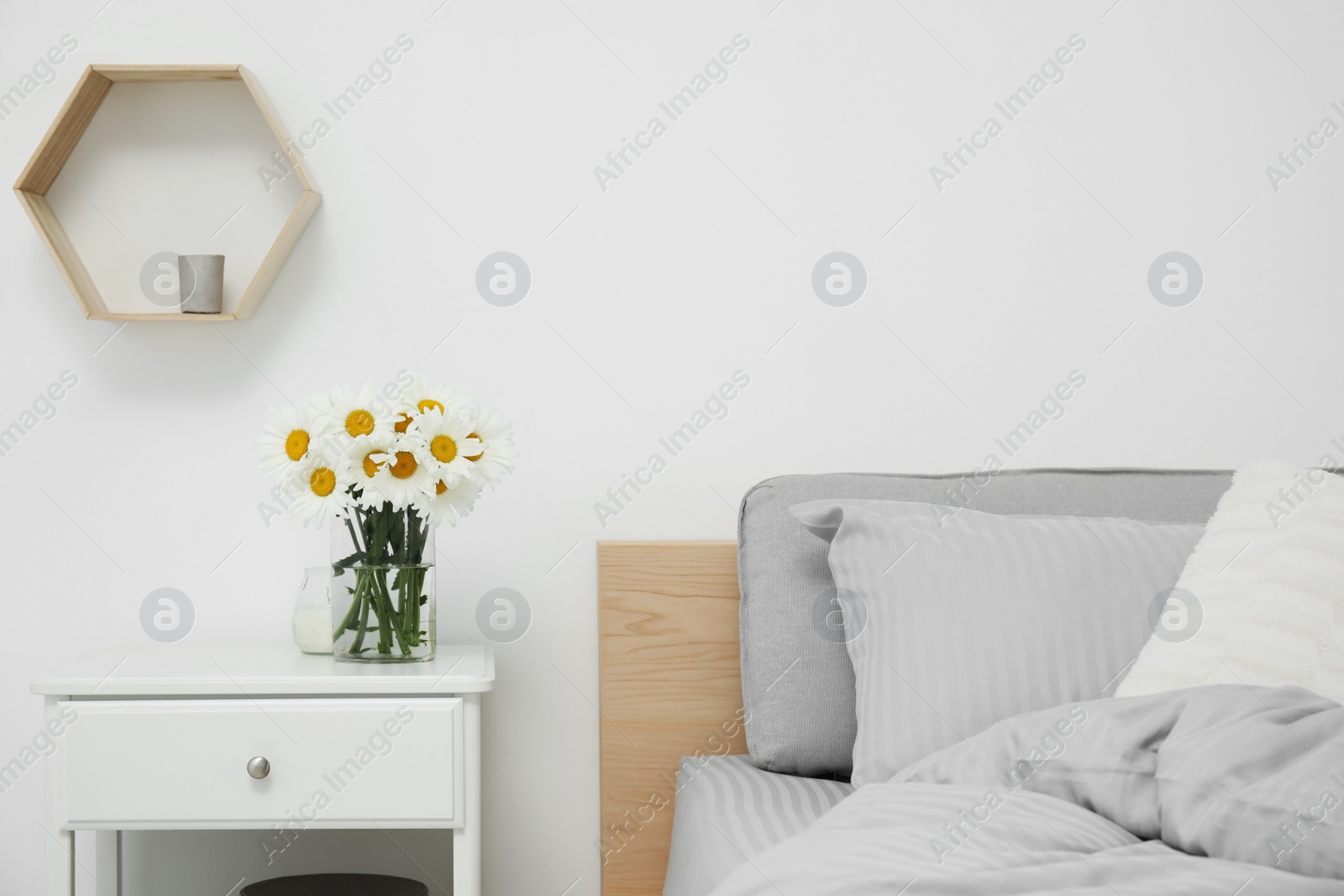 Photo of Bouquet of beautiful daisy flowers on nightstand in bedroom