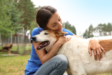 Photo of Female volunteer with homeless dog at animal shelter outdoors