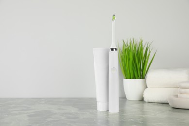 Electric toothbrush and tube with paste on light grey marble table
