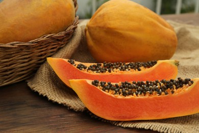 Tasty whole and cut papaya fruits on wooden table