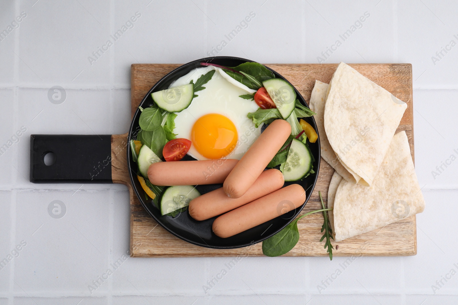 Photo of Delicious breakfast with boiled sausages and fried egg on white tiled table, top view