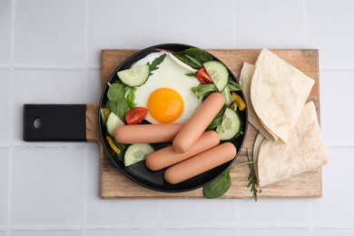 Photo of Delicious breakfast with boiled sausages and fried egg on white tiled table, top view