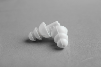 Photo of Pair of white ear plugs on grey background, closeup