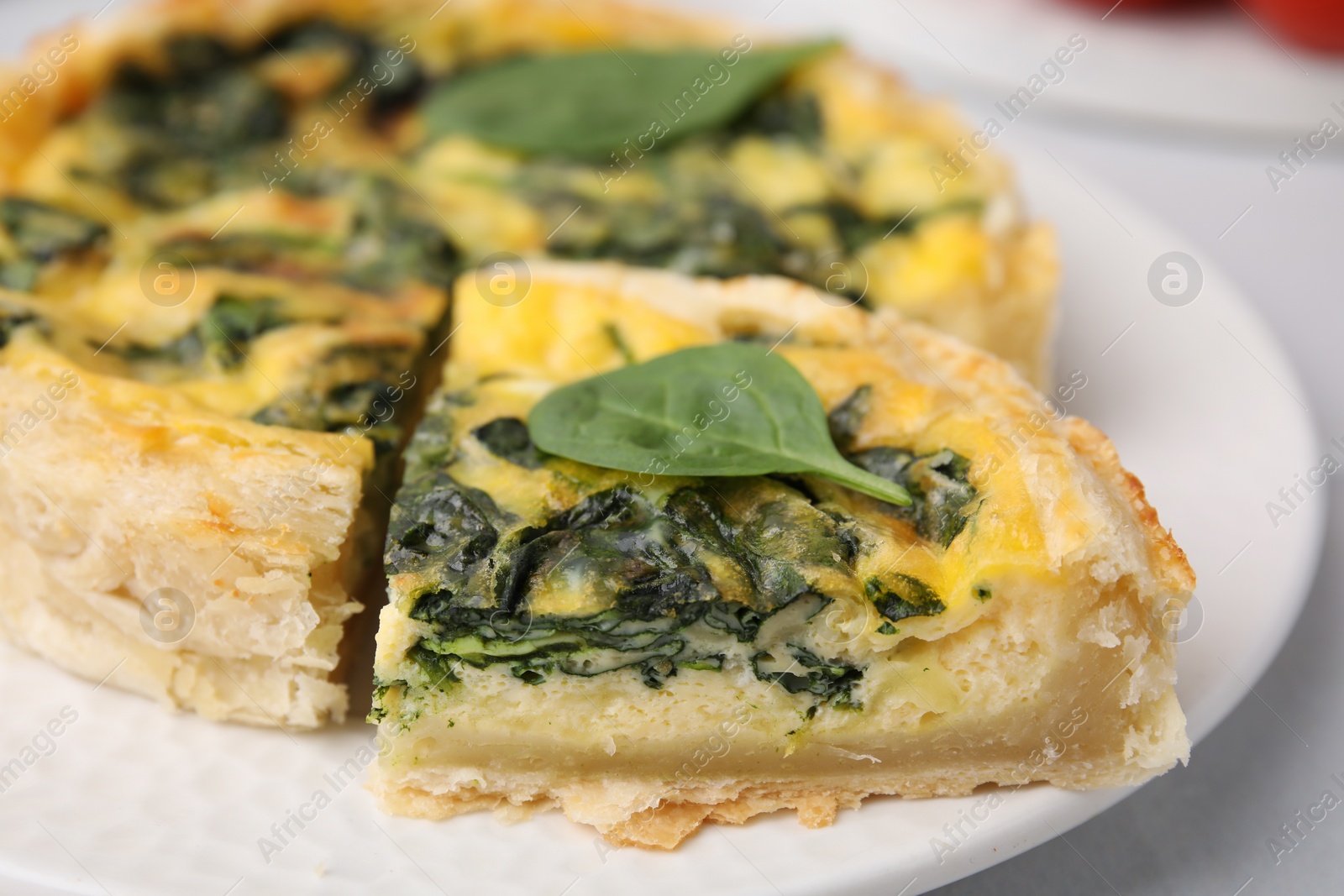 Photo of Delicious pie with spinach on white table, closeup