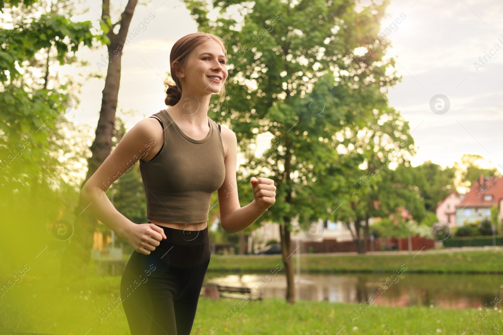 Photo of Teenage girl jogging around park in morning. Space for text