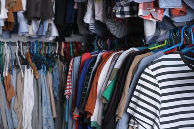 Photo of Hangers with stylish clothes on racks as background, closeup. Fast fashion