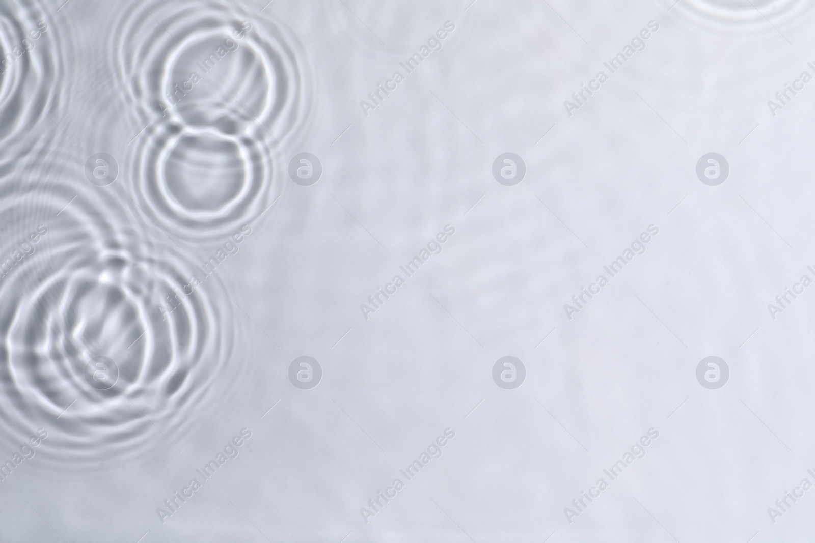 Photo of Closeup view of water with circles on light background. Space for text