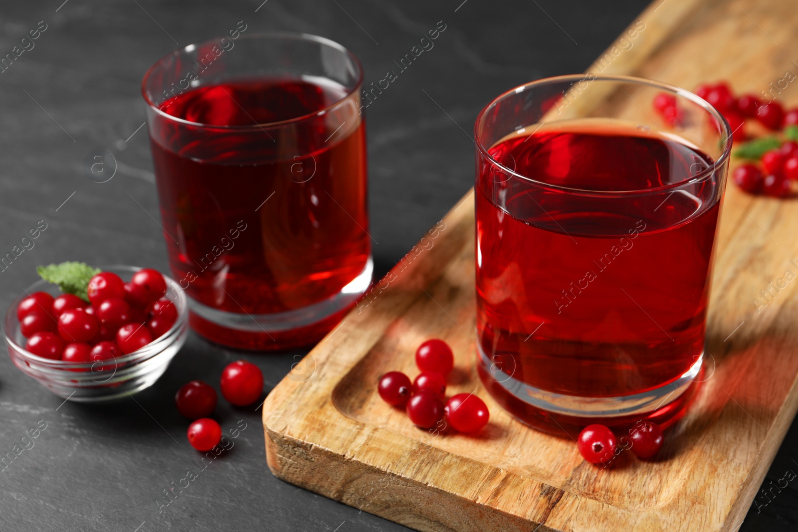 Photo of Tasty refreshing cranberry juice and fresh berries on grey textured table